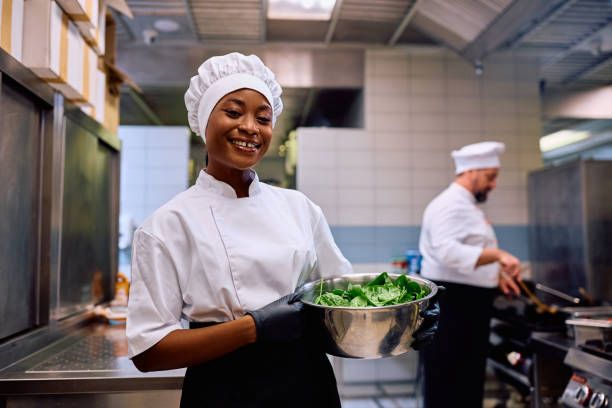 Chef holding a bowl of fresh greens in the kitchen